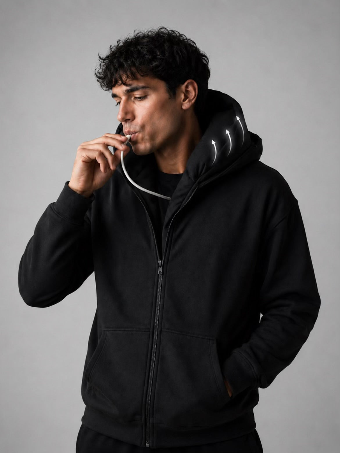 Man inflating a built-in neck pillow inside a black hoodie